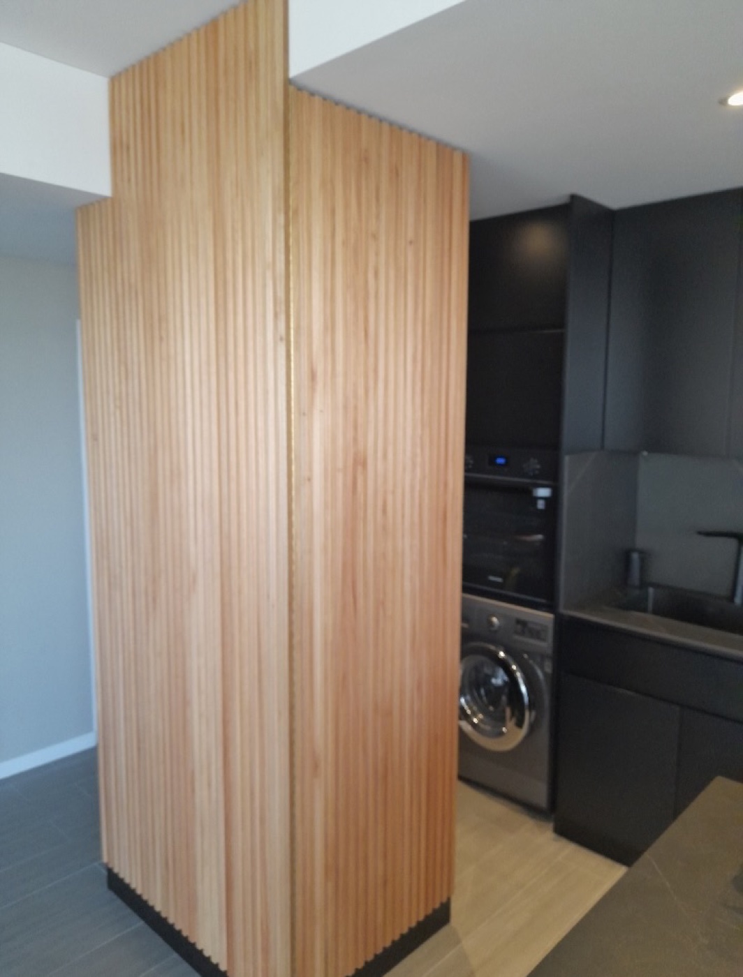 Columna de lamas de madera junto a cocina negra